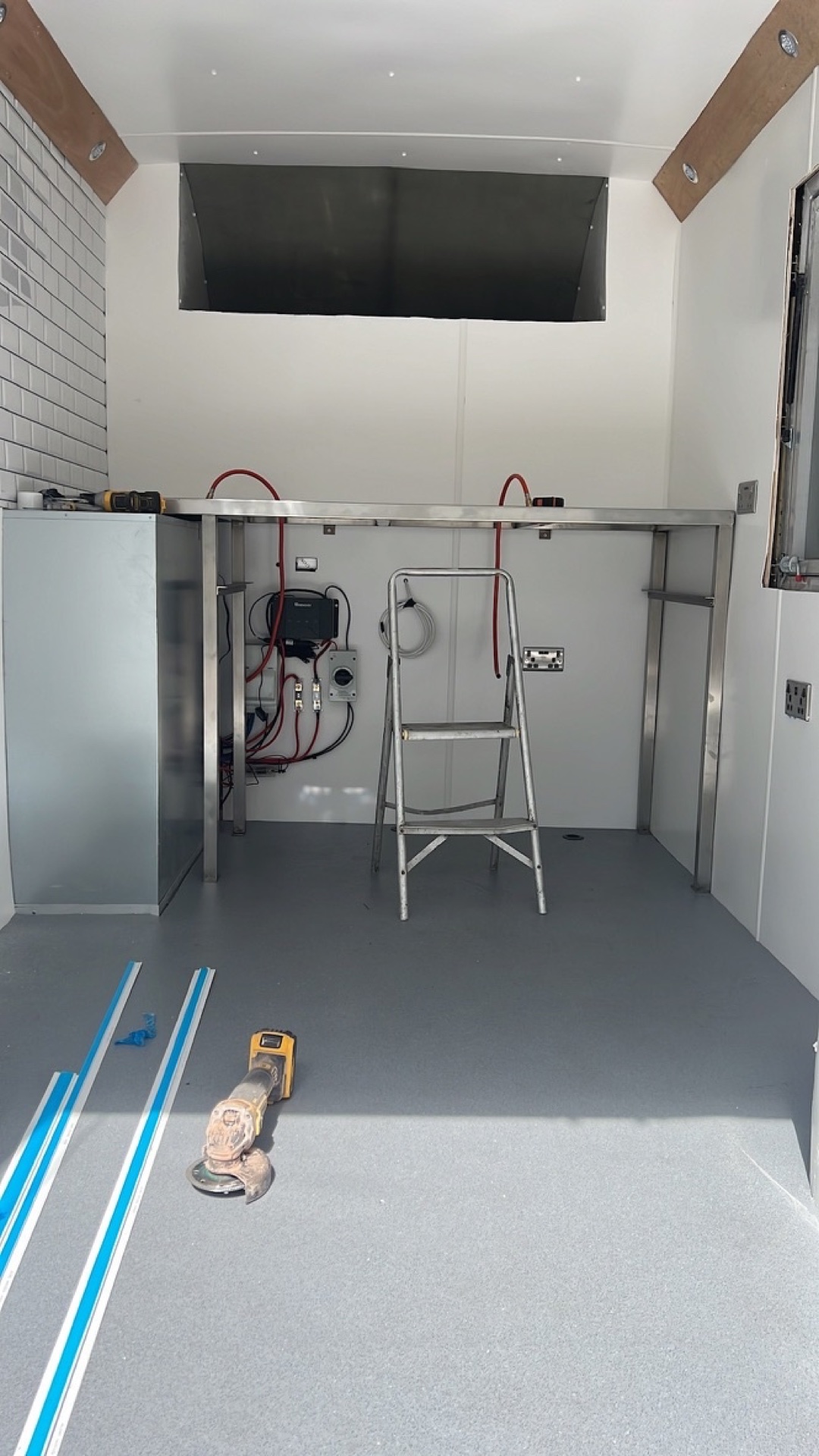 Van interior painted white with a grey vinyl floor, stainless counter and metro tiled wall