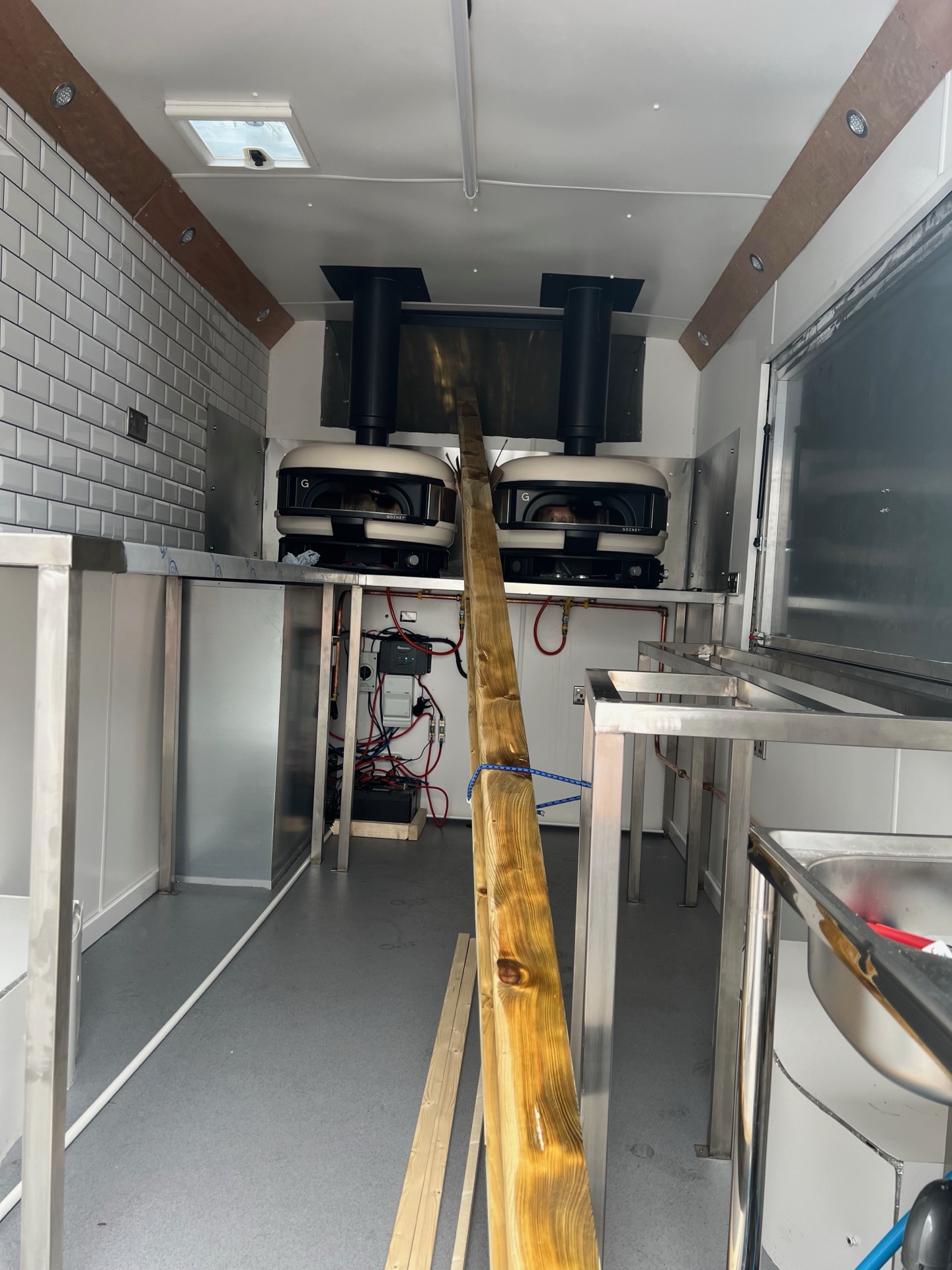 Two Gozney pizza ovens installed side by side in the van with flues going up through the roof