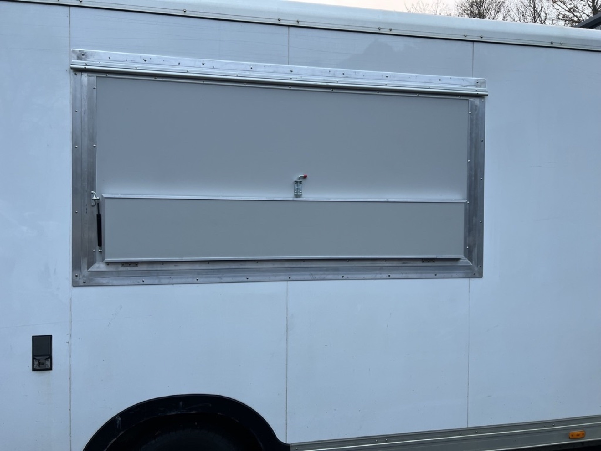 Serving hatch cut into the side of the van and framed in aluminium