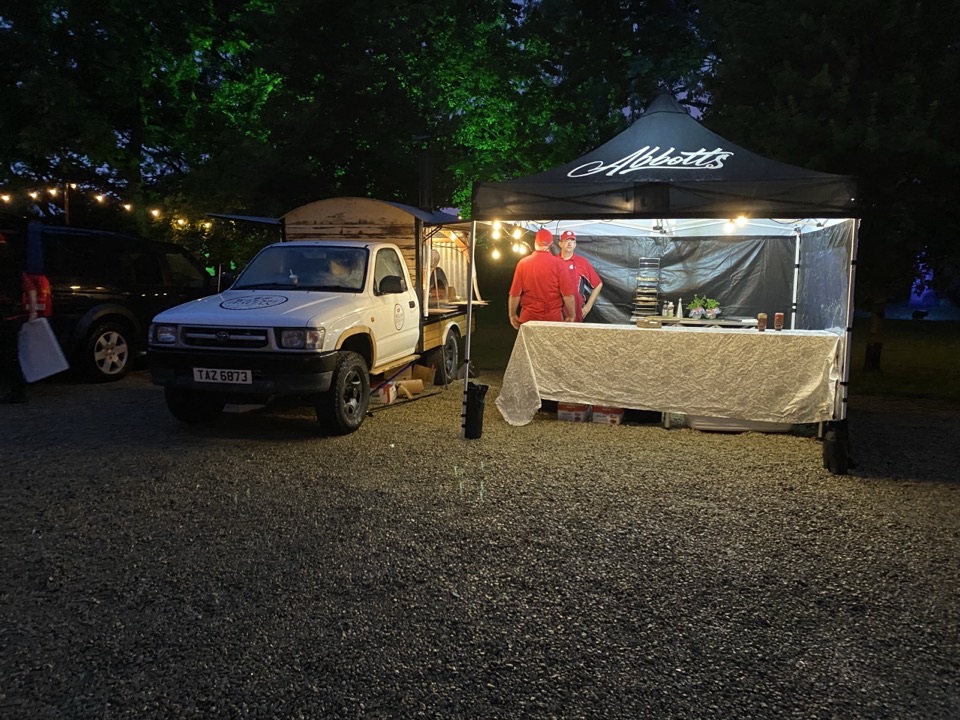Evening corporate pizza service with the white truck, branded canopy and crew in red uniforms