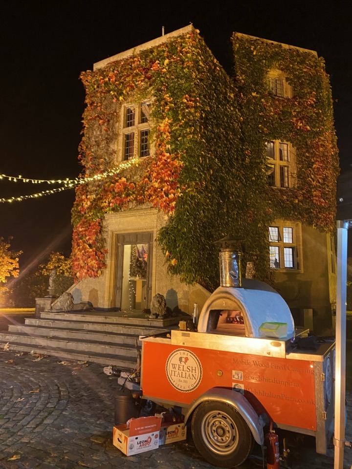 The branded oven trailer outside a house lit with festoon lights at a private party