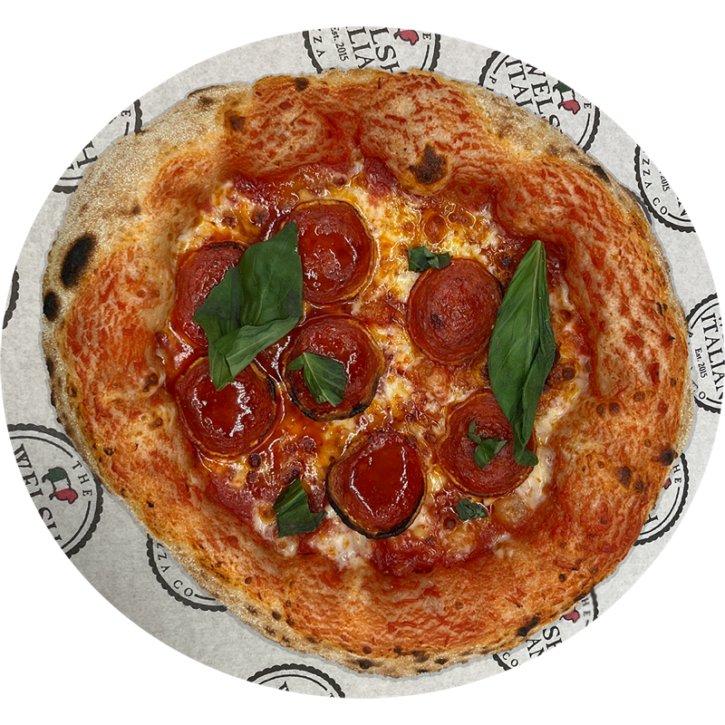 A pepperoni pizza finished with fresh basil