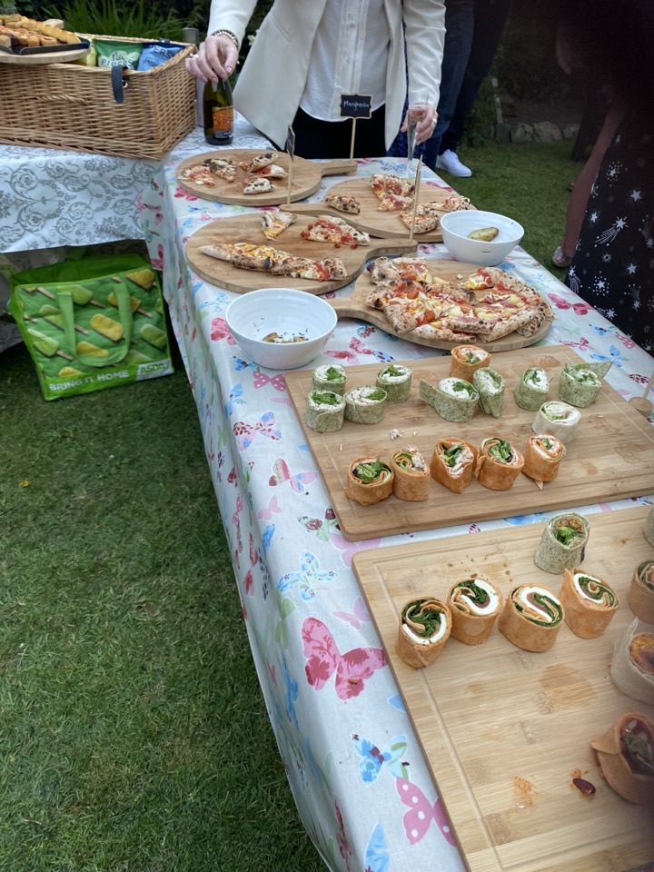 A buffet table of sliced pizzas on boards with sides laid out alongside