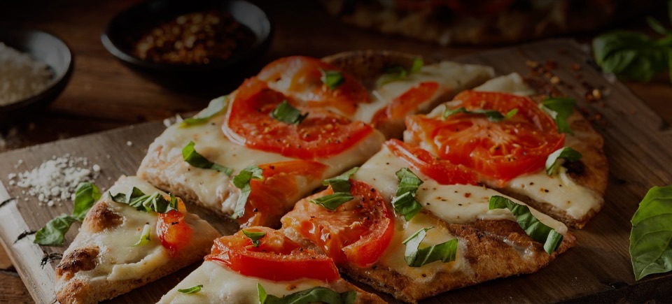 A sliced pizza with tomato, mozzarella and basil on a wooden board