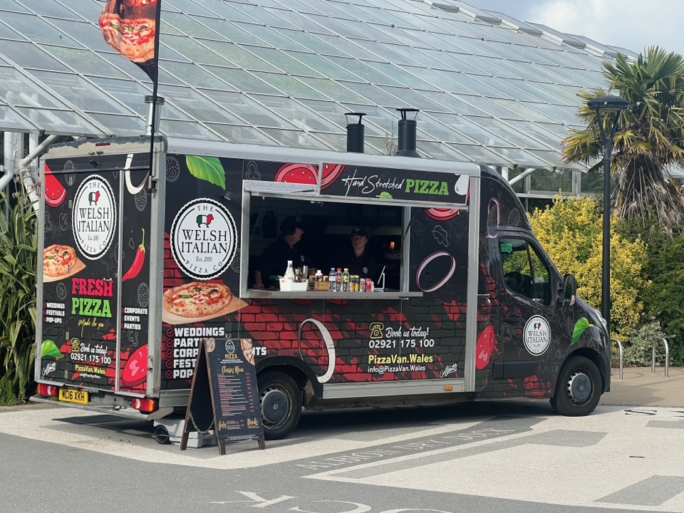 The wrapped pizza van with its serving hatch open at an event