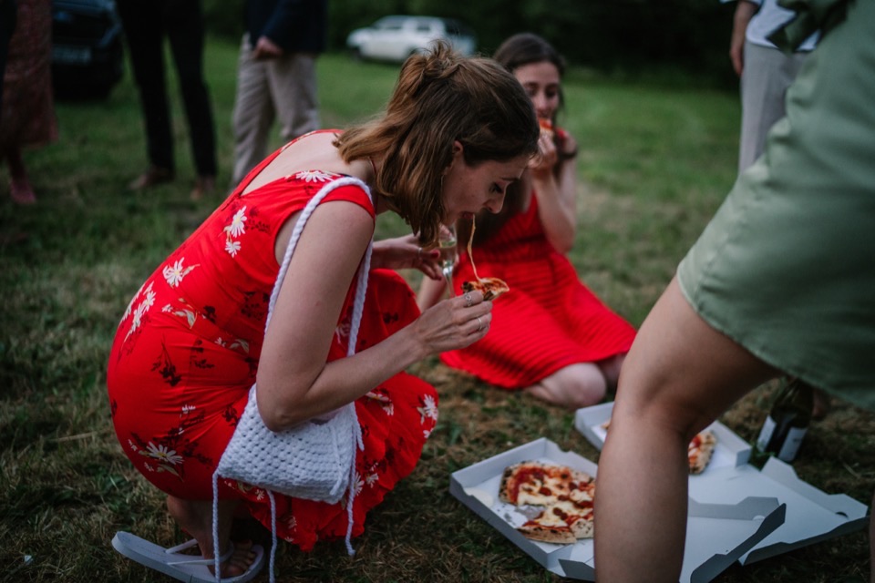 Wedding guests in the evening eating pizza from boxes on the grass